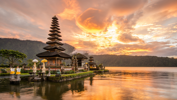 Ulun Danu Beratan Temple in Bali, Indonesia, surrounded by water with a dramatic sunset sky in the background
